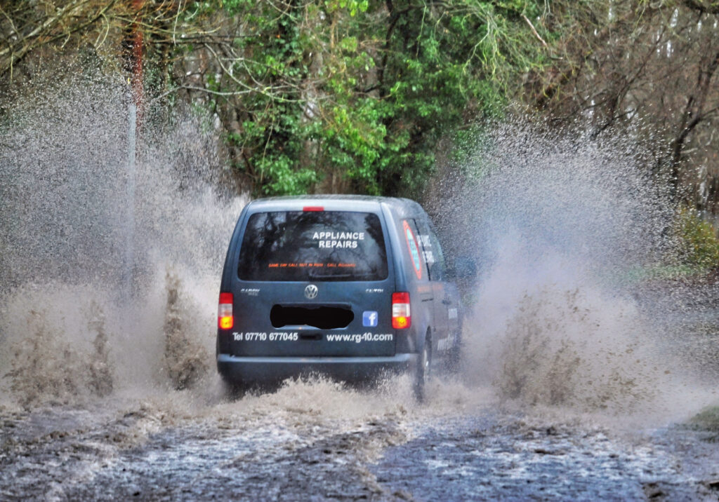 Car runs thru flooded street