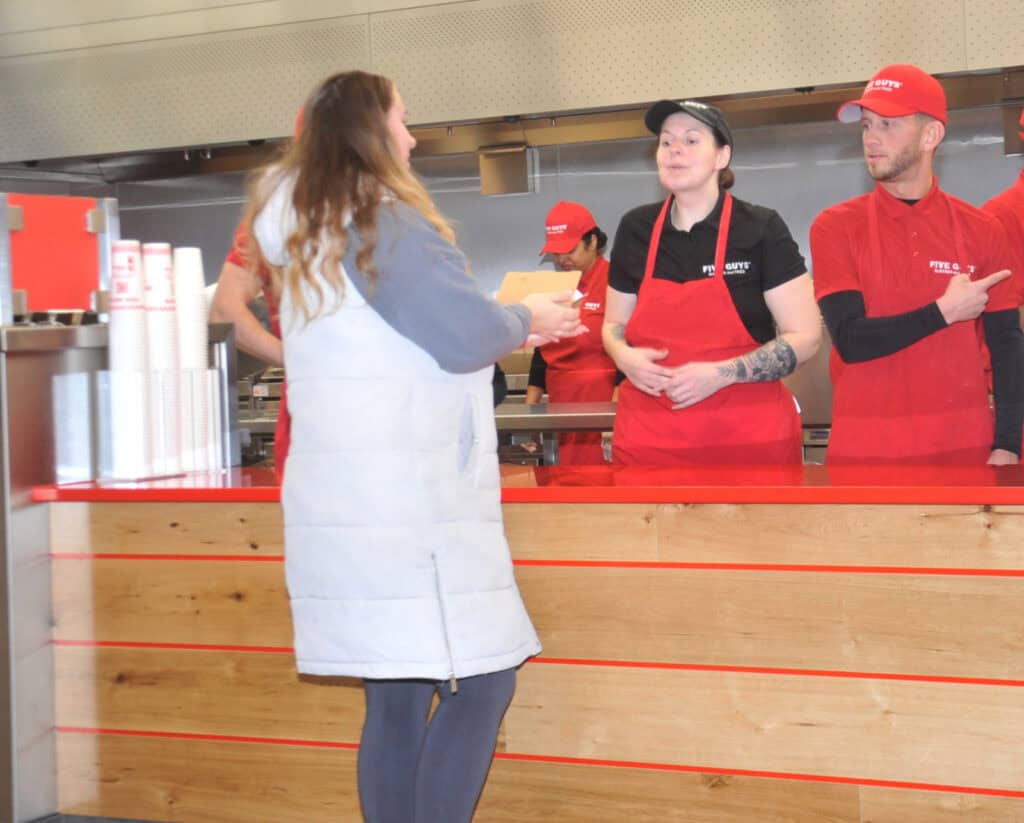 Customer interacts with staff at Five Guys Wokingham restaurant opening event.